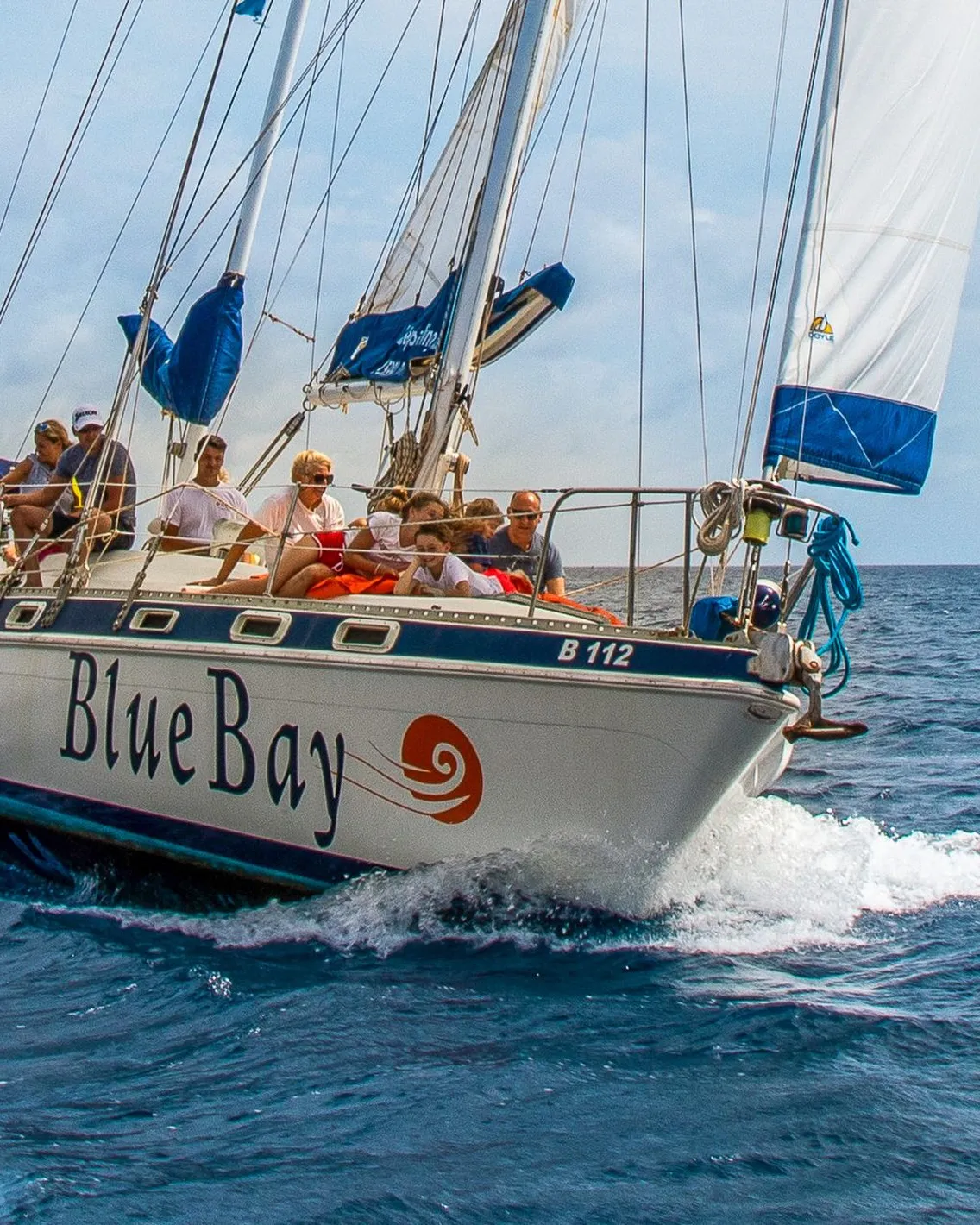 The Blue Bay Bonaire sailboat under full sail, with guests on deck